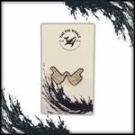 An enamel pin featuring two hands forming a 'Flying W' gesture, displayed on branded backing card packaging from 'The Pin Whale.' The card features a minimalist design with a black brushstroke wave graphic and a logo of a whale above the pin, adding a unique alt-rock-inspired aesthetic.